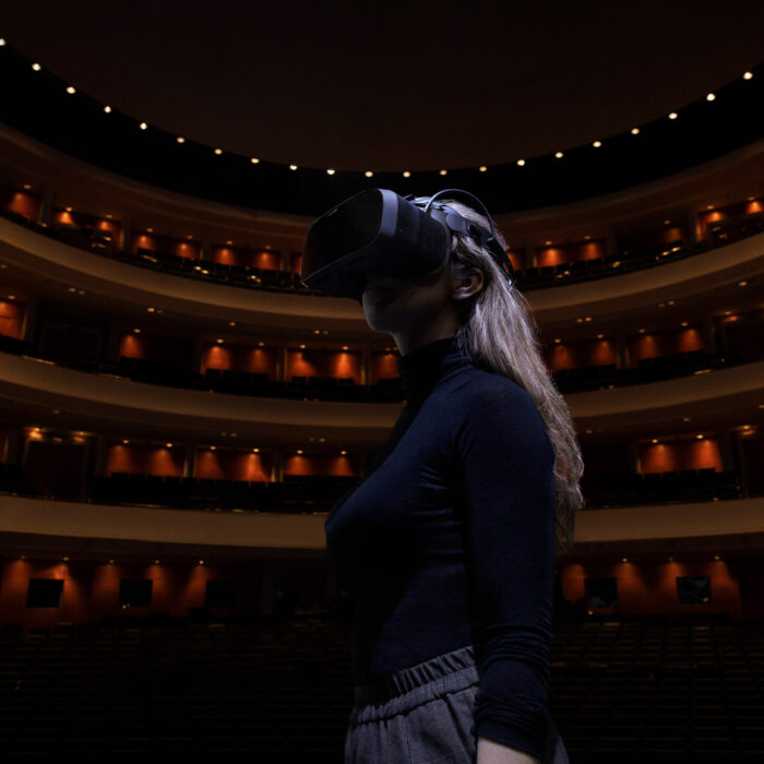 This is a photo of a woman with XR headset standing on stage at FNOB opera house.